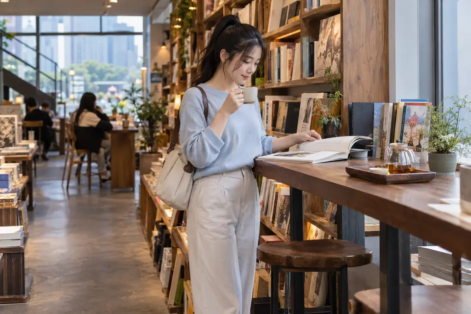 长沙独立书店内，一位年轻女性坐在窗边阅读，手边放着茶杯